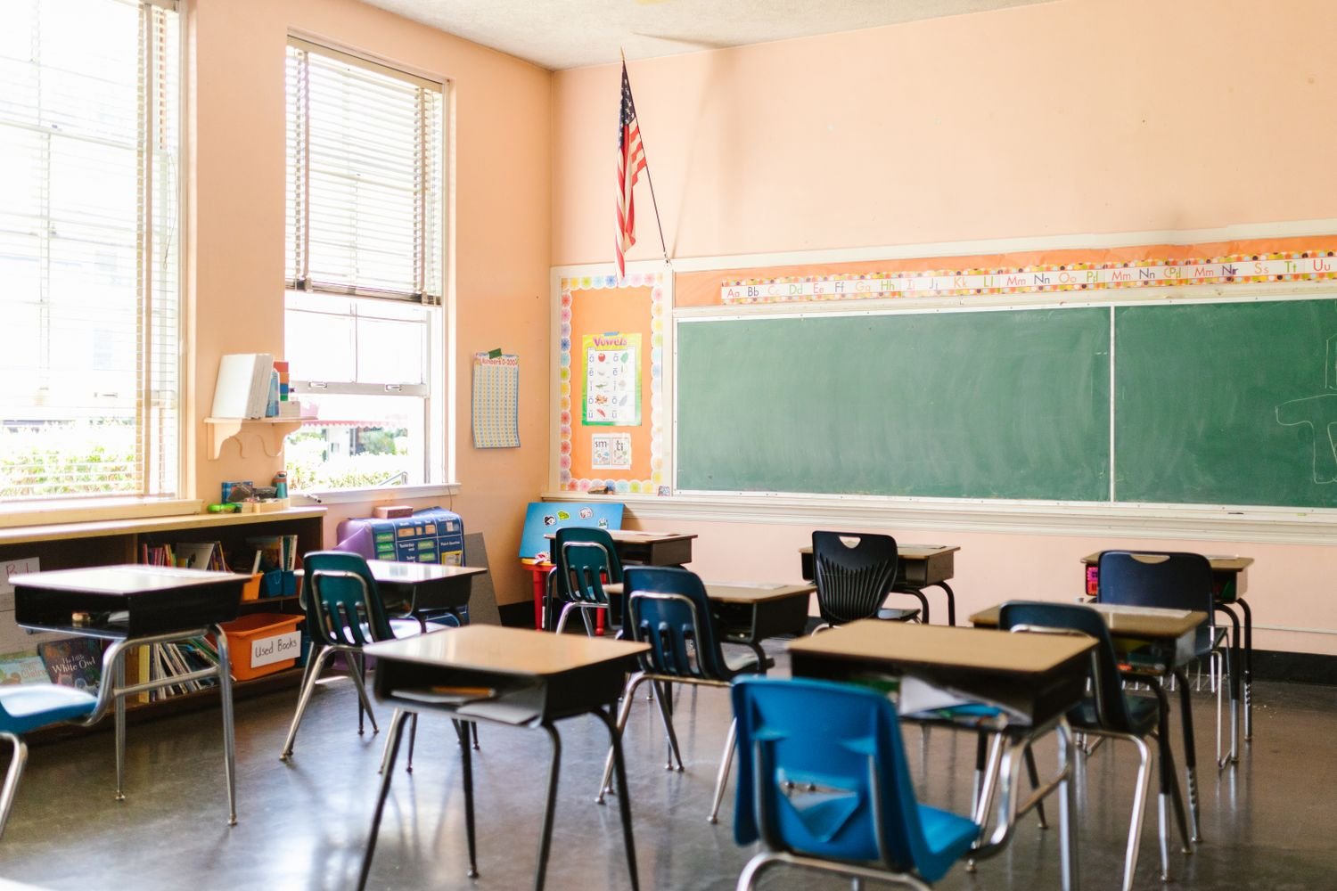 Sunlit classroom with empty desks and an American flag