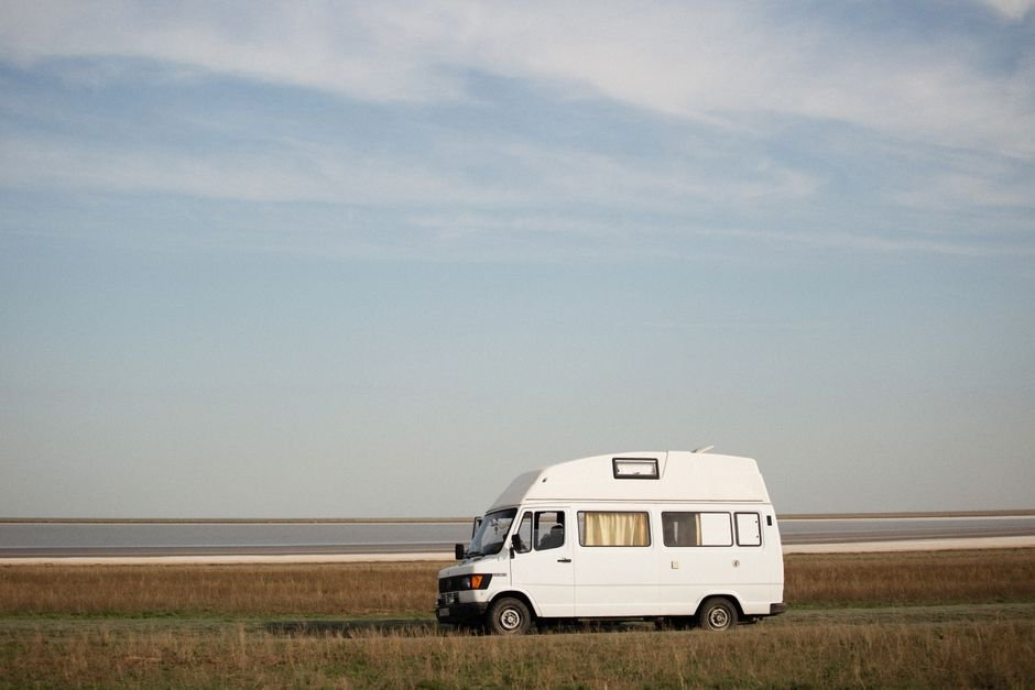 Camper van parked in an open flat field, similar to rental units available in the Algona, Iowa area