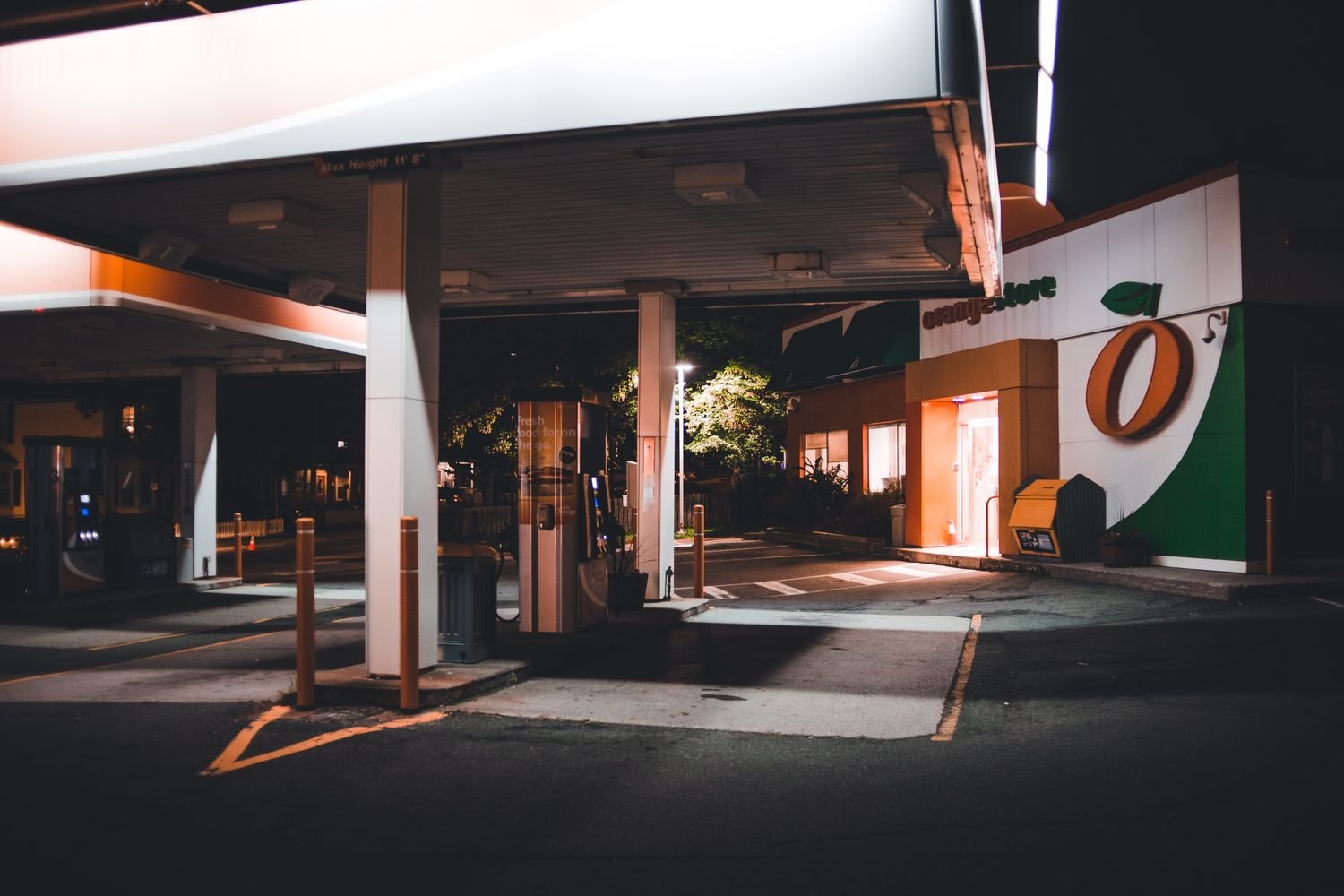 Empty gas station forecourt with overhead lighting at dusk