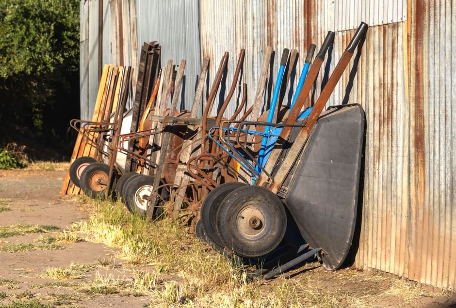 Wheelbarrows and farm tools lined up against a metal shed, similar to farm and ranch supplies at Bomgaars in Algona, Iowa