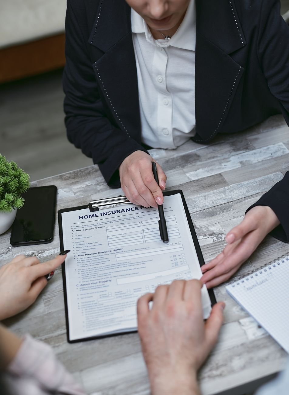 Insurance agent discussing home insurance paperwork with clients at a desk