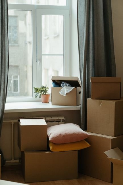Moving boxes stacked in a sunlit new apartment before utilities are set up
