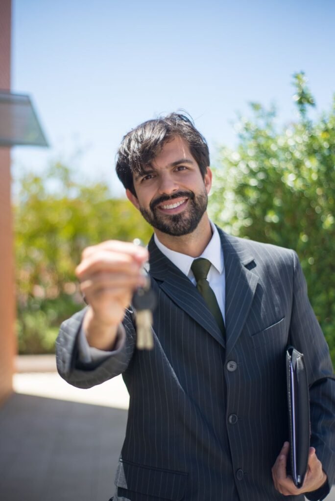 Real estate agent presenting a house key outdoors after a home sale