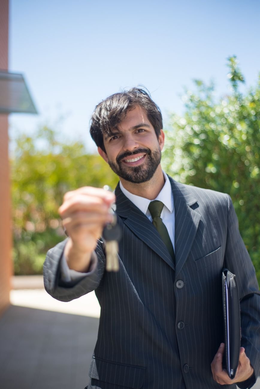 Real estate agent presenting a house key outdoors after a home sale