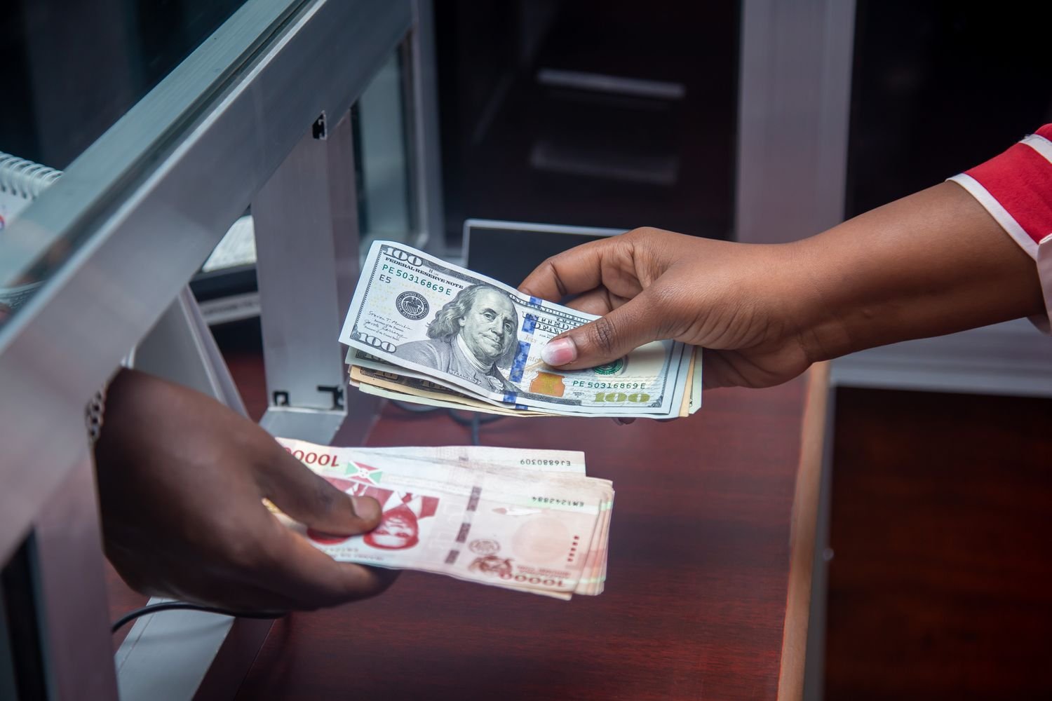 Hands exchanging currency at a bank counter